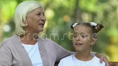 奶奶和孙女坐在公园里开心地聊天，一家人